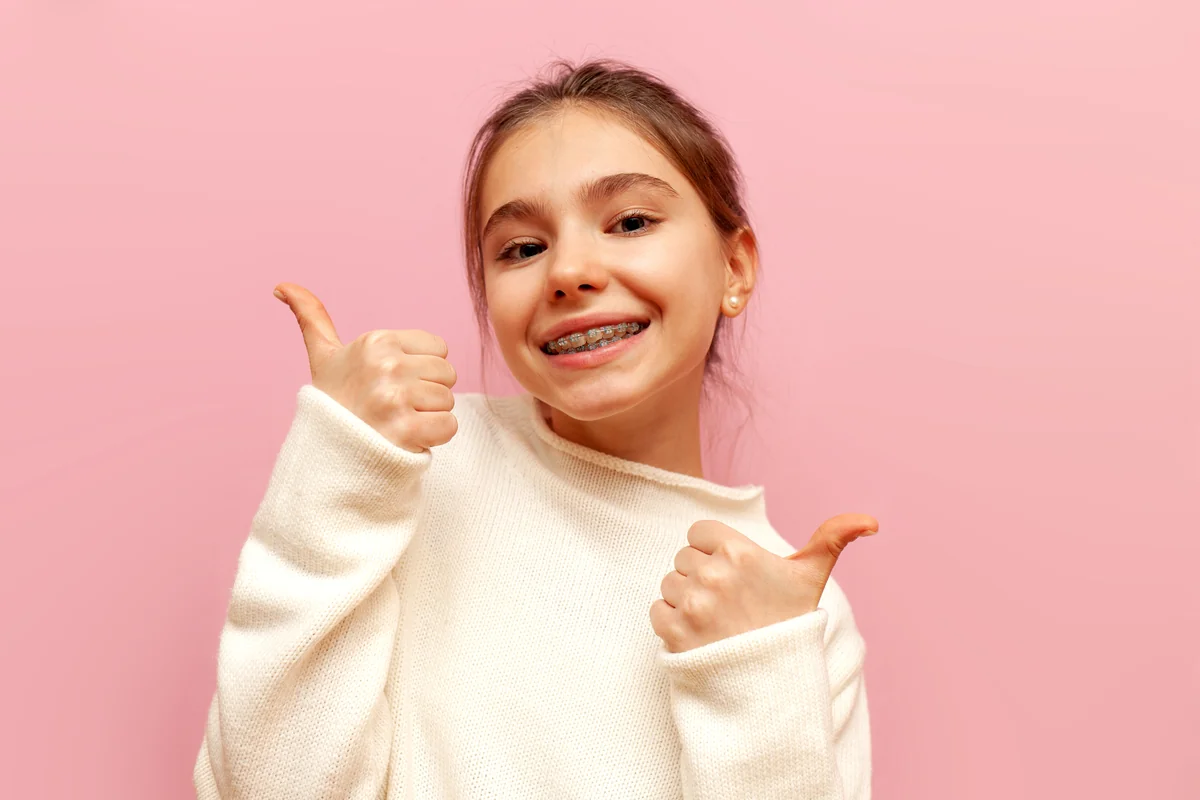 Smiling teen with braces giving two thumbs up